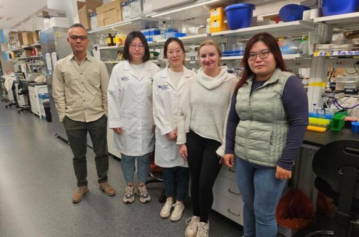 Ka Wing Fong standing in his lab with other researchers