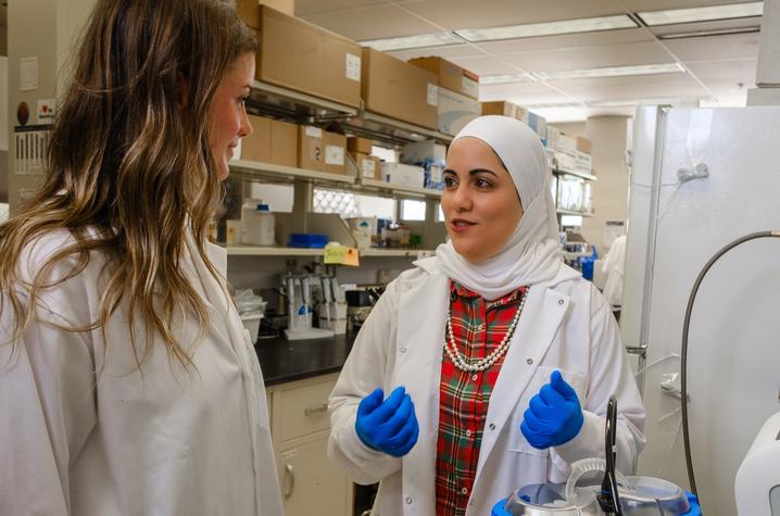 Yosra Helmy, right, speaks with another researcher in a lab.