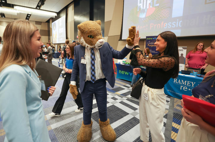 The UK wildcat mascot at a career fair with attendees