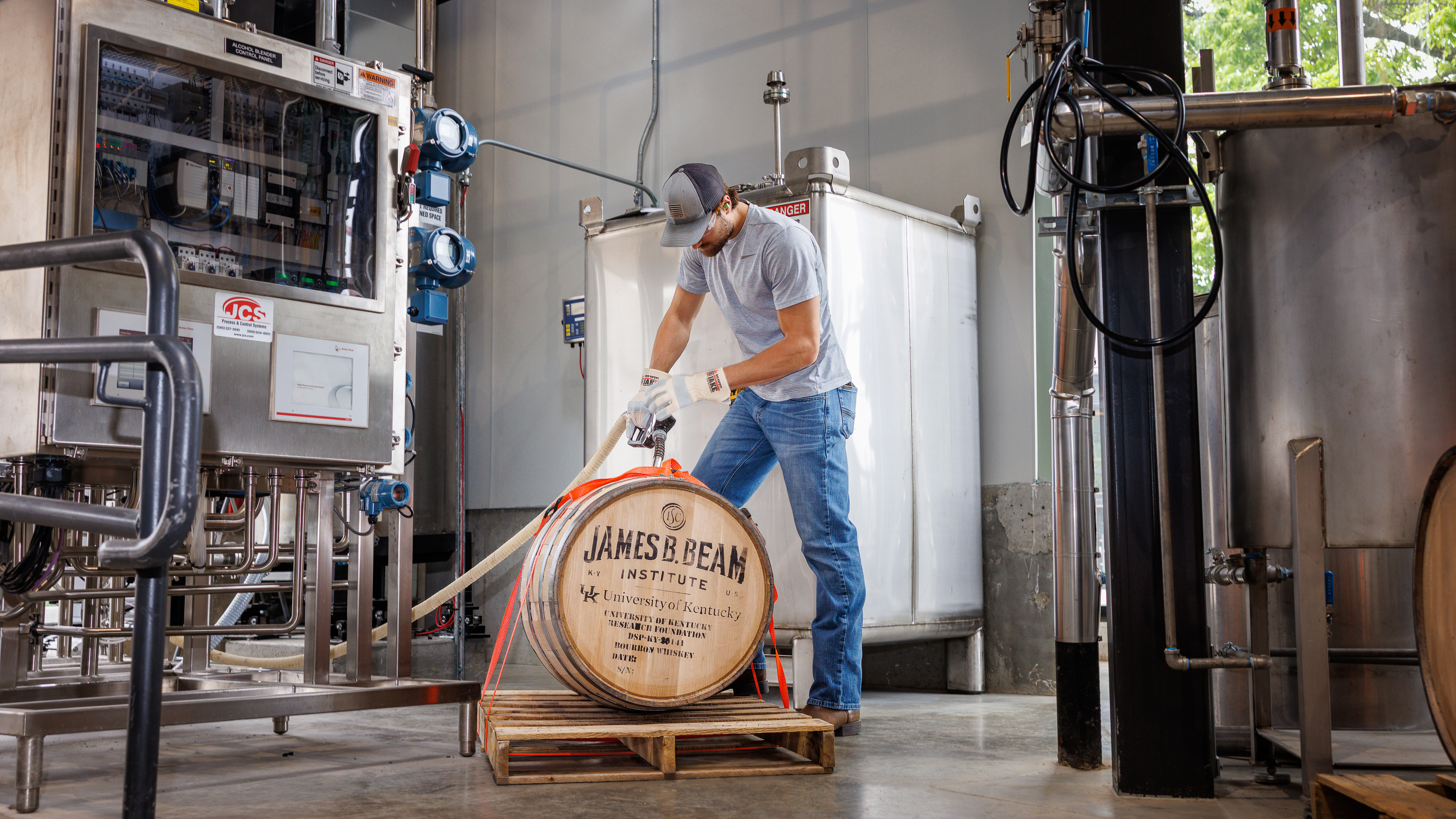 a distillery worker fills a Jim Beam barrel