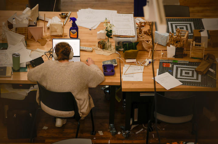 overhead image of a student working on their laptop in a design studio