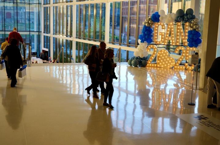 Conference attendees walk past an illuminated sign for the 2025 Gill Affiliate Network conference