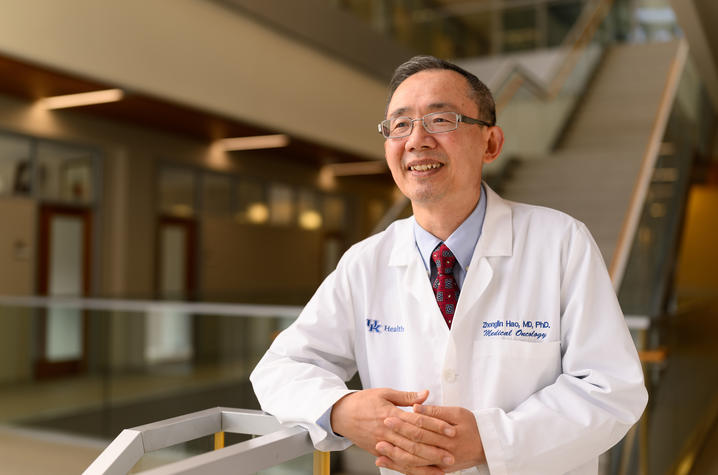 Zhonglin Hao stands near a stairway while wearing a white lab coat