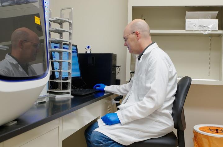 Allen Page sits at a computer in a laboratory