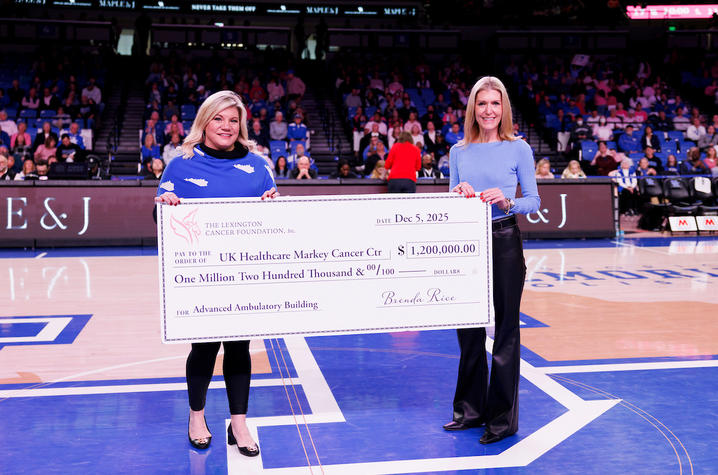 Lisa Mahan and Kristi Martin present a $1.2 million check on a UK basketball court