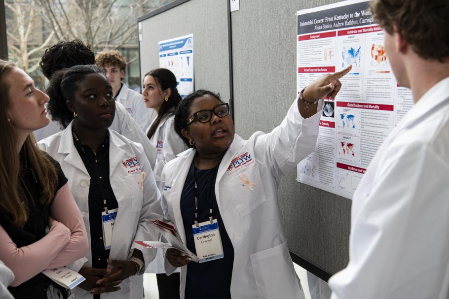 researchers point out details on a poster to conference attendees