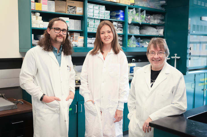 Caleb Bailey, McKenna Green and Linda Van Eldik stand in a lab