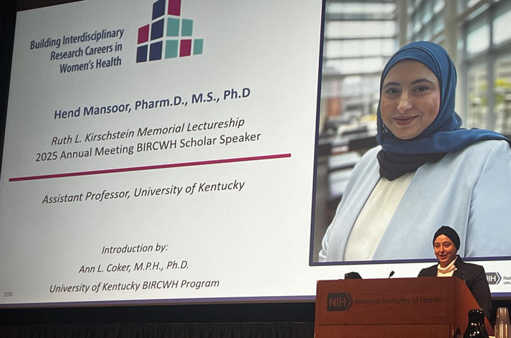 Hend Mansoor speaking at a podium on stage