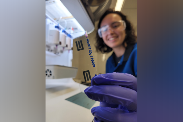 Paula Alarcon-Espejo, a graduate research assistant at UK's Center for Applied Energy Research, holds a slide with a printed carbon nanotube/conducting polymer composite electrode pattern for making a printed OECT.