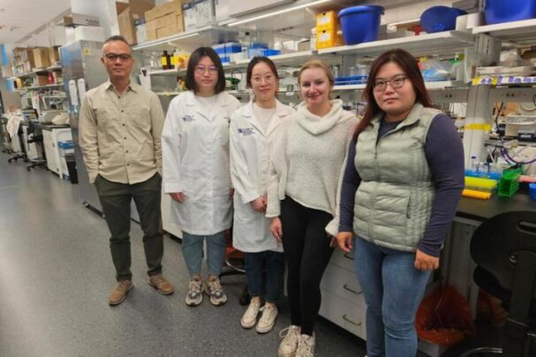 Ka Wing Fong standing in his lab with other researchers