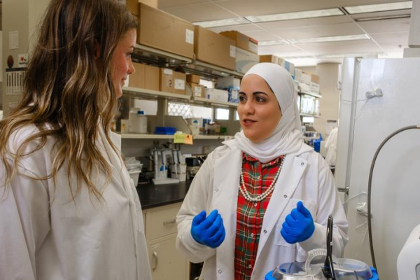 Yosra Helmy, right, speaks with another researcher in a lab.