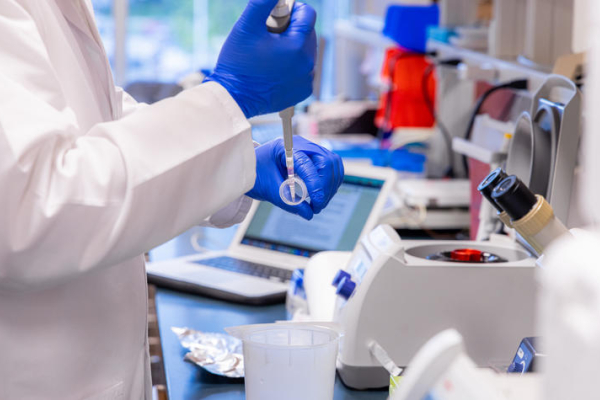 a scientist in a lab transferring a sample to a tube