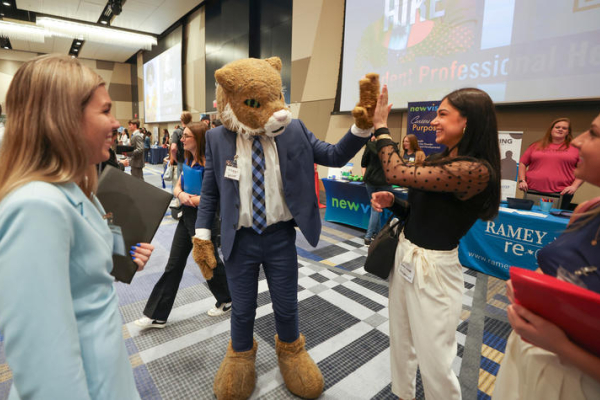 The UK wildcat mascot at a career fair with attendees