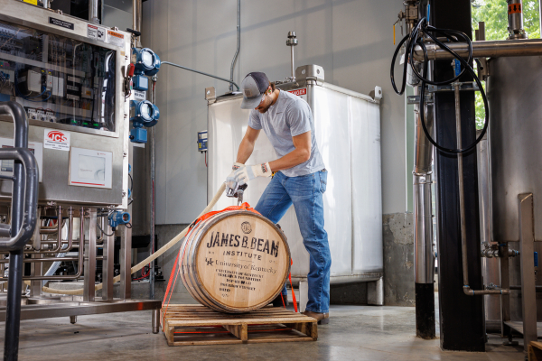 a distillery worker fills a Jim Beam barrel