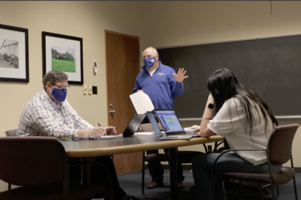 Wayne Sanderson talking to others in a meeting room
