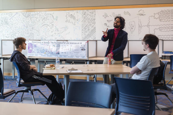 Shane D’Souza talks with UK biology undergraduates in front of his whiteboard mural in the Michael & Susan Scott Biology Learning Center in the Don & Cathy Jacobs Science Building.