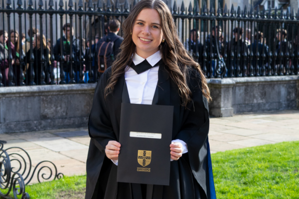 Gretchen Ruschman in graduation regalia, holding a degree from Cambridge University 