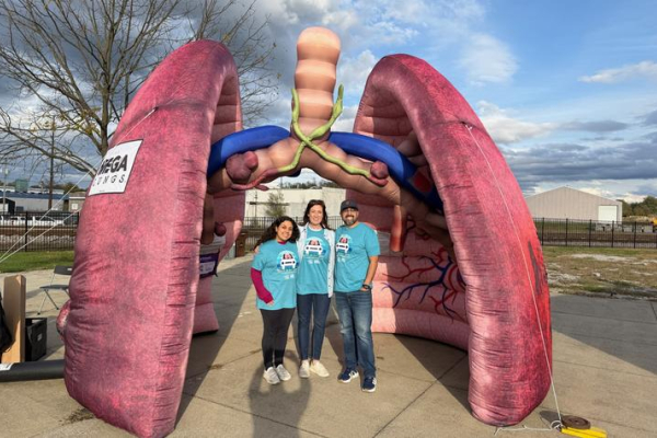 A group of people stand under a large, inflatable model of lungs