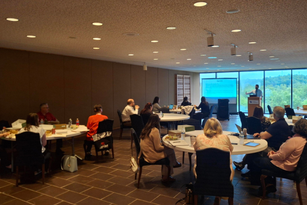 people at round tables listening to a presenter at a University of Kentucky lectern