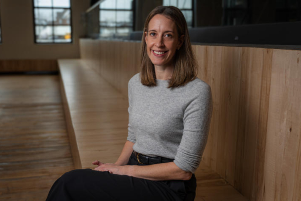 Kristi Bartlett sits on a long, wooden bench indoors