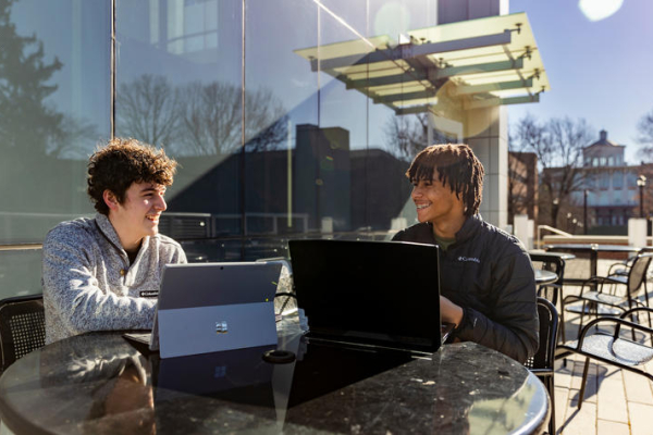 students on laptops at an outdoor table