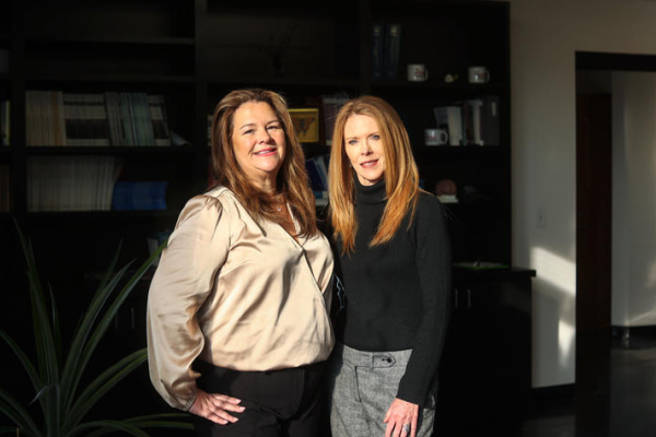 Carrie Oser and Michele Staton stand in a darkened room