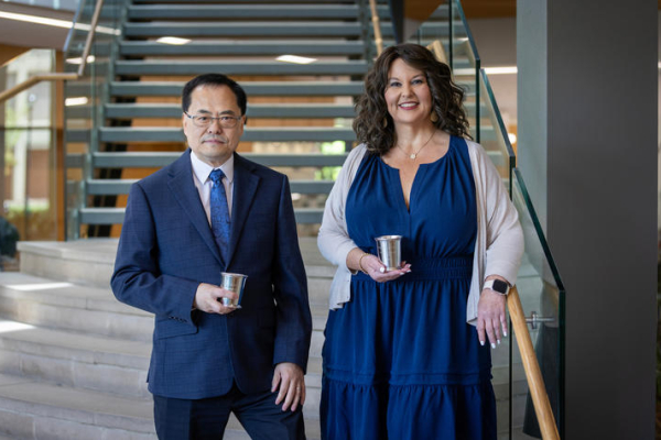 two people holding awards near a stairway