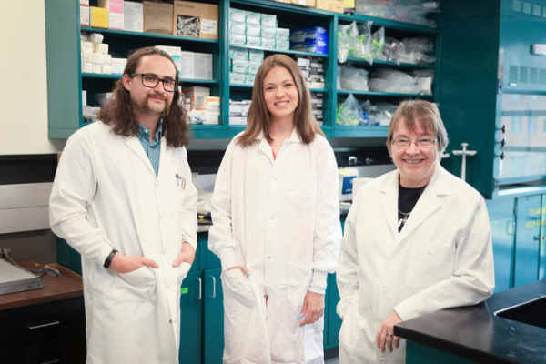Caleb Bailey, McKenna Green and Linda Van Eldik stand in a lab
