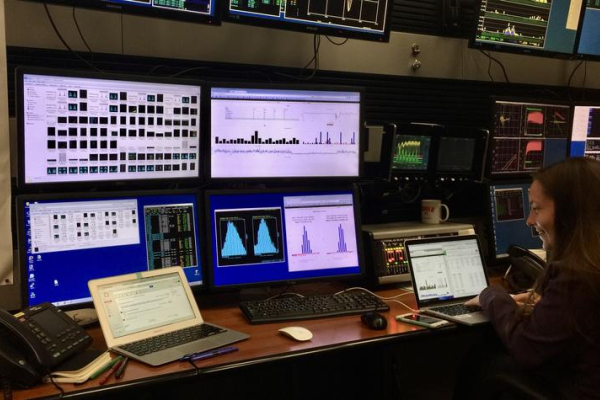 a researcher in a room filled with multiple computer screens displaying graphs