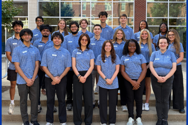 a group of students in matching shirts stand in front of a building