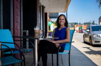 Picture of UK associate professor of epidemiology April Young sitting outside the Fuzzy Duck cafe in Morehead, Ky.