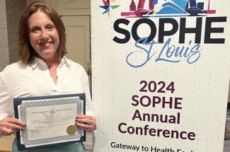 Lauren Batey holds her Health Education & Behavior Paper of the Year Award for 2023.