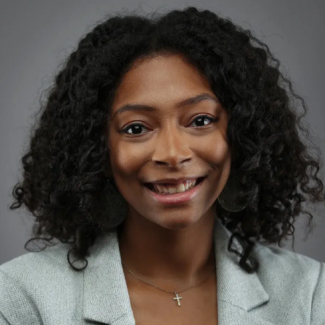 Image of Meagan Scott, a black women with shoulder length black curly hair wearing a gray blazer