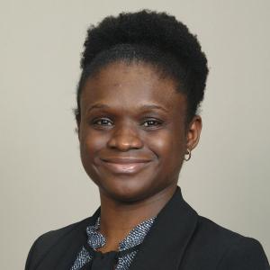 Image of Jenny Lutshumba, a black women with short curly hair, wearing a black blazer.