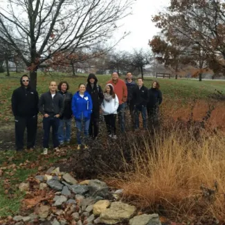 people standing outdoors near tall grass and rocks