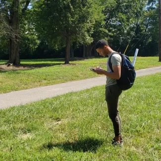 Person taking notes while standing in a field near a path