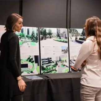 Two people standing at a display board with building concept drawings