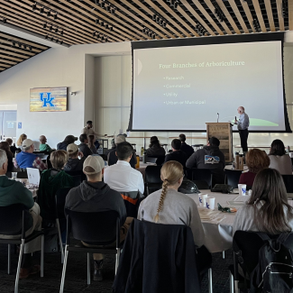 A lecture at Canopy Con - the presentation reads "Four Branches of Arboriculture: Research, Commercial, Utility, and Urban or Municipal"