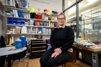Jennifer Meakins sits in a studio space surrounded by colorful spools of thread