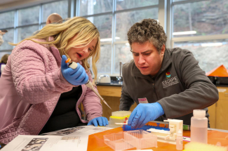 A student places water samples in test tubes with the help of a university researcher