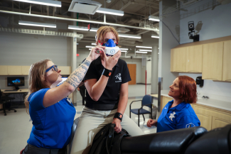 two researchers fitting a respirator to a jockey on a mechanical horse in a lab