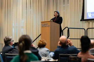 Molly Blasing presents on stage behind a University of Kentucky podium