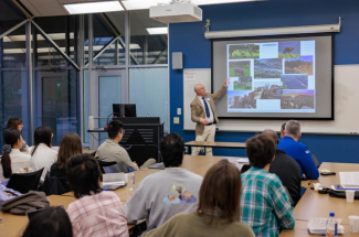 Jorge Ruiz-Carrascal points to screen while presenting to a room of spectators
