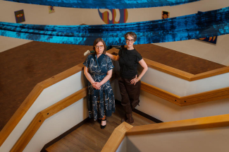 two people standing on a stairway landing overlooking an art gallery