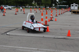 a student drives an EV cart around a corner marked with orange traffic cones