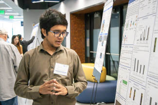a person standing near a research poster in a symposium hall