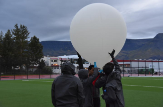 a team of researchers hold up a weather balloon outside