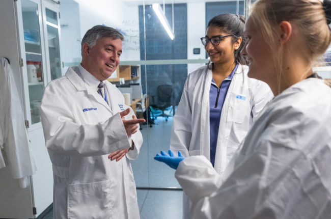 Simon Fisher talks with two research students in a lab