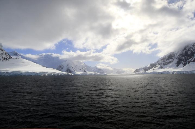 calm water in Antarctica with snow-covered rockfaces on either side