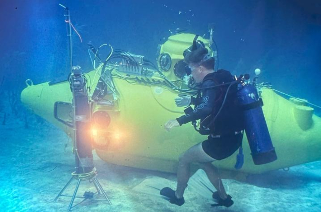 a diver underwater next to the Nekton Gamma submersible